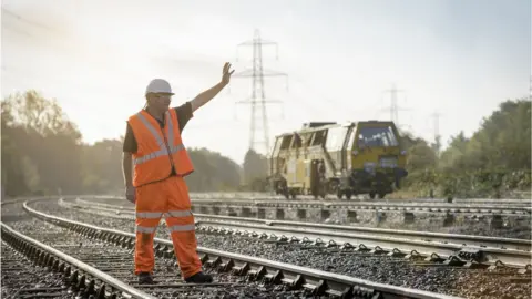 Getty Images Man in hi-vis and helmet on a railway track