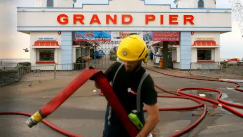 Getty Images A fireman is seen at work in front of the burnt out Weston Super-Mare pier, Somerset on July 28, 2008