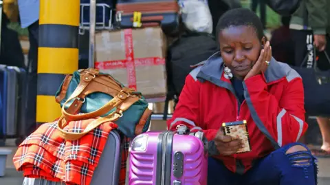  Peter Njoroge/BBC Passengers wait at a closed door at the departures of the Jomo Kenyatta International Airport (JKIA) in Nairobi 