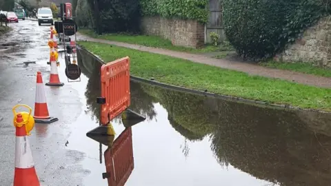 Gary Liddle A flooded road which is closed off by orange traffic cones.