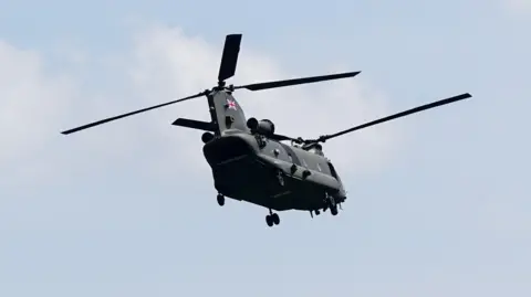 PA Media A Chinook helicopter is seen in flight. It has a Union Jack flag on its rear rotor column.