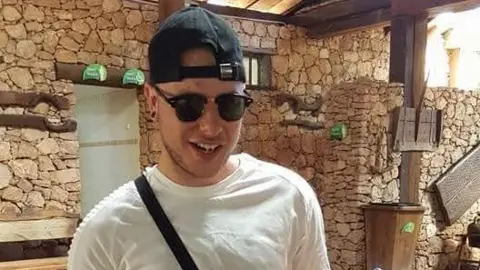 Family Tyran Jones in an old photo wearing sunglasses and a cap backwards. He is smiling. 