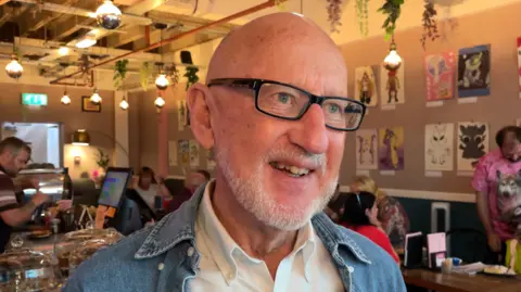 Tim Gittins is at the Out Together charity morning wearing a denim jacket and white shirt.