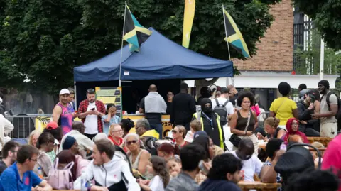 Coventry City Council Crowds of people enjoying a festival sitting on benches infront of a main stage