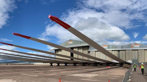 Large blades of wind turbine outside a shed, waiting to be installed