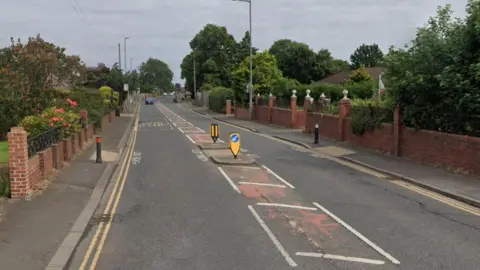 Thornaby Road in Stockton. There is a traffic island in the middle of the road with bollards on the pavements on either side. Rows of houses line the street.