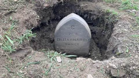 A marker stone with the inscription C 754 Dr Barnardo owner on it