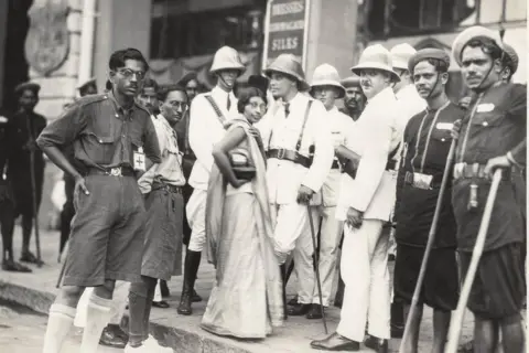 Alkazi Collection of Photography In this monochrome photo, Lilavati Munshi, a Congress leader from Gujarat, stands defiantly outside a boycotted British store in Mumbai. She is wearing a sari and glasses, and is surrounded by the police