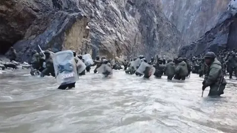 Getty Images This video frame grab taken from footage recorded in mid-June 2020 and released by China Central Television (CCTV) on February 20, 2021 shows Indian soldiers crossing a river during an incident where Chinese and Indian troops clashed in the Line of Actual Control (LAC) in the Galwan Valley, in the Karakoram Mountains in the Himalayas