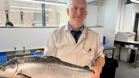Fishmonger holding a salmon.