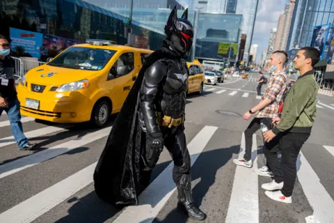Alexi Rosenfeld / Getty Images A cosplayer dressed as Batman wearing the Hellbat suit crosses the road during Day 1 of New York Comic Con at Javits Center on 7 October 2021 in New York City.