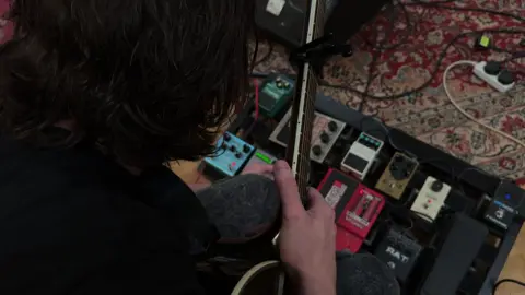 James fiddles with his pedal board.