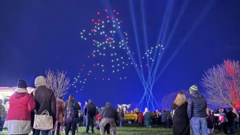 Abbie Louise Homer People standing in the Ardingly South of England showground look at an image of what might be a teddy bear created in the sky by drones.