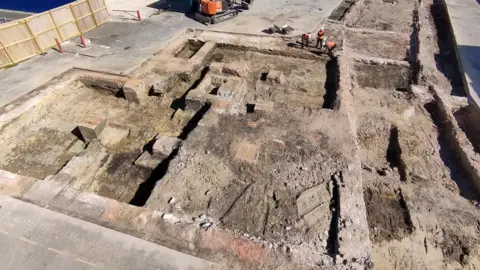 Context One Ariel view of the empty dig site before the volunteers arrive. Several structures are visible in the trenches that have been uncovered in the old car park.