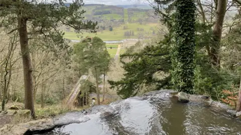 The view of Chatsworth and the gardens from the hillside above