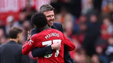 Manchester United manager Michael Carrick and Kobbie Mainoo hug