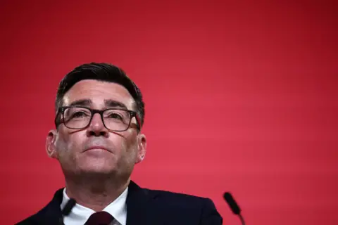 Andy Burnham against a red background