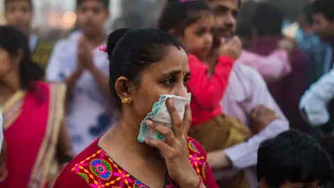 Getty Images Woman shields her nose from smoke