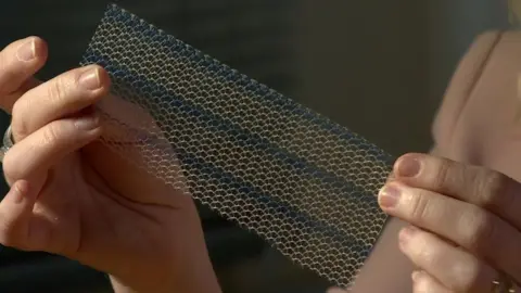 BBC Reporter holding up a surgical mesh