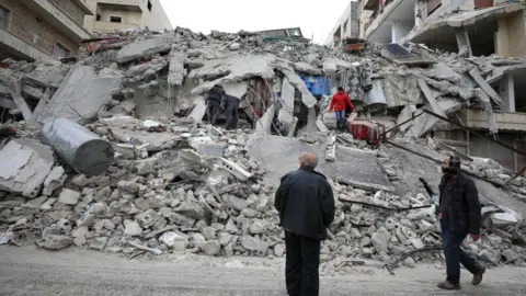 Rescuers work at the site of a collapsed building in Idlib