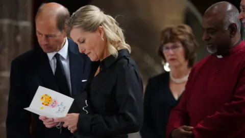 PA Media The Earl and Countess of Wessex reading a condolence card at Manchester Cathedral