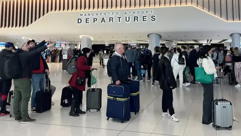 Reuters Passengers queuing at Manchester Airport