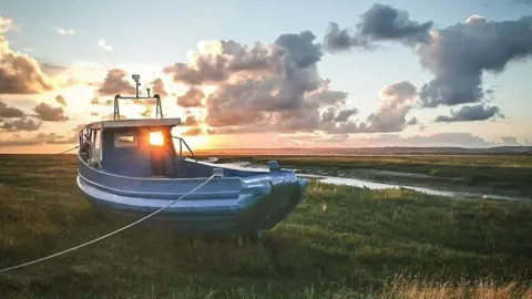 Ashley Williams A fishing boat tied up on the grass near Crofty in Swansea