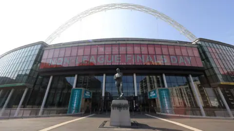 The Bobby Moore statue outside the front of Wembley. The arch is towering above the stadium and the sign reads "Welcome to Non-League Finals Day".