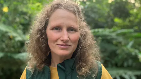 Woman with curly hair with a backdrop of plants in the rainforest biome