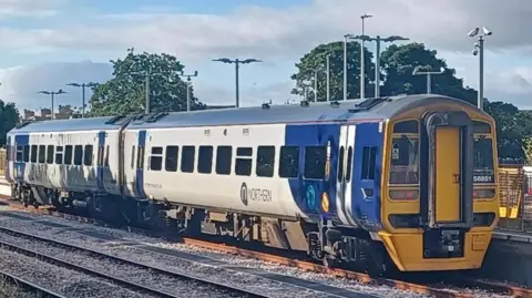Northern train, in blue and white livery, stands at a station.