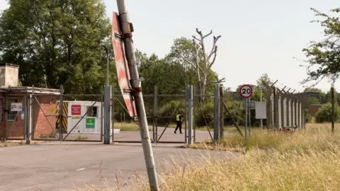 A closed gate and wire fencing around a disused military site near the village of Piddington in Oxfordshire.  