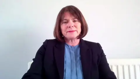 Michelle Skeer sits against a white wall.