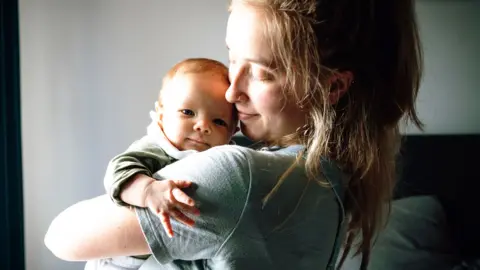 A young mother holding a baby