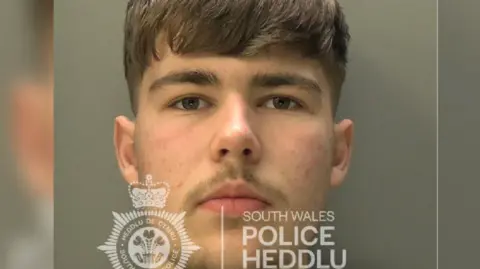 South Wales Police Harley Whiteman mugshot, he has a thick brown fringe and moustache and is looking directly at camera