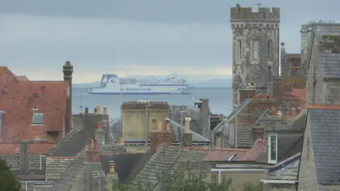 The Brittany Ferries passenger ferry can be seen in Poole Harbour, with a number of building tops in Purbeck in the foreground