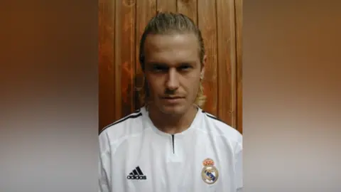 Andy Harmer A man in a white football kit. He is dressed as David Beckham.