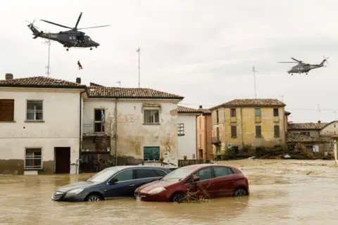 Carros Getty em águas inundadas com helicópteros acima