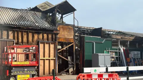 Julia Gregory/BBC The charred remains of part of a roof on a platform at Paignton station is visible in this image. The stairs over the track are also visible and the roof over them is charred.