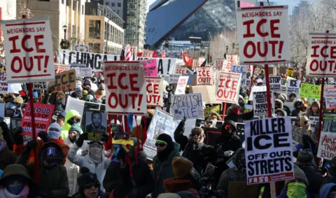 A number of anti-ICE protesters hold up signs during a demonstration 
