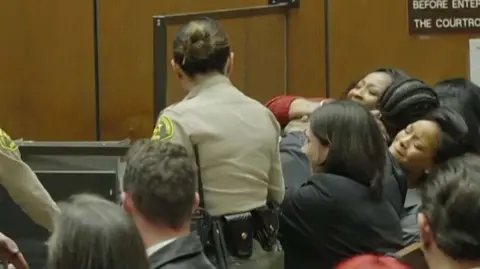 A$AP Rocky embraces an emotional Rihanna as court officers look on