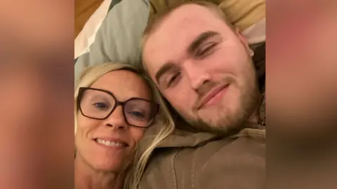 Family Handout Two people are lying close together on a sofa, with pillows behind them. One person is wearing glasses. The other has a beard and a light‑coloured jacket.