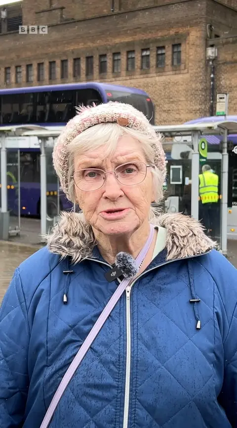Marlene Ames, an older woman, wearing a blue coat, looking at the camera