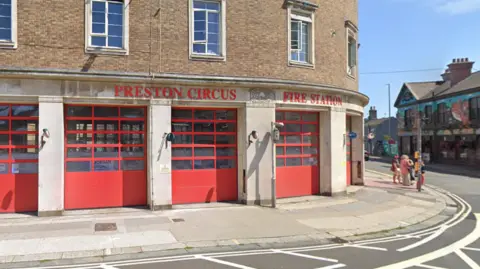 A curved brick building with five red garage-style doors. 