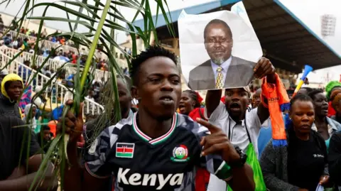 Reuters Mourners hold palms and Odinga's portrait walking into a stadium 