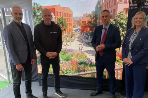 Hull City Council Three men and four women stand in front of a screen with a computer generated impression of a new housing development.