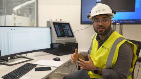 Ihab Amed está sentado em frente a terminais de computador explicando como o teste do motor a jato funcionará.