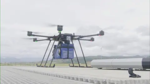 Inteliports An image of a drone with its propellers whirling around as it sits on a roof of a container