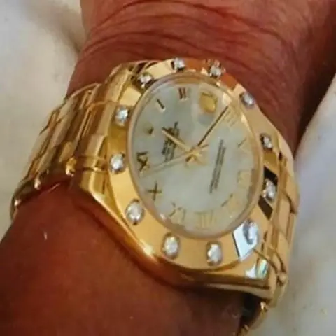 Metropolitan Police A close-up of a gold wristwatch with a diamond-studded bezel and Roman numerals on the dial, worn on a tanned wrist.