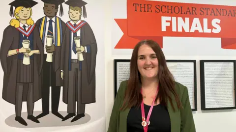 Marine Academy head teacher Jen Brimming smiles with the top row of her teeth showing in front of a mural of three pupils - two boys and a girl - with graduation gowns and mortar boards on. Jen has long, straight brown hair on and is wearing a black top with a green jacket.