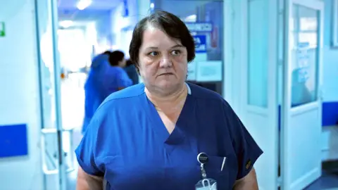 Surgeon Dr Oana Goidescu on shift at Buzău Hospital in blue scrubs. She has mid length black hair